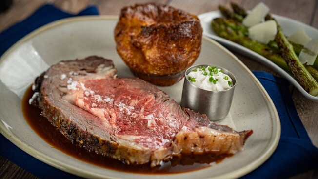 A piece of prime rib served with a side of hash and vegetables 