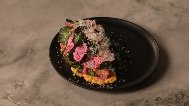 Verduras y remolachas cortadas en rodajas finas encima de una base de granos en un plato