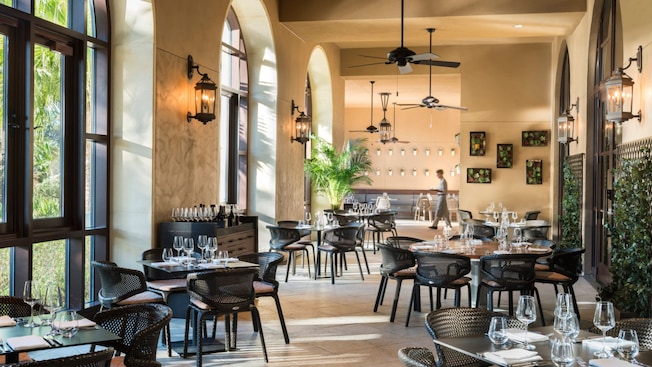 A sunlit dining room with tables set for service in Ravello at the Four Seasons Resort Orlando
