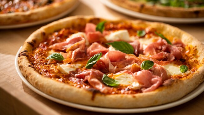 Three pizzas including one with prosciutto, fresh mozzarella and basil