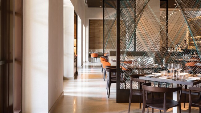 A sunlit dining room with tables set for service in Ravello at the Four Seasons Resort Orlando