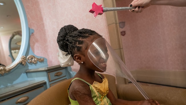 A young girl wearing a Disney Princess gown while receiving a makeover at Bibbidi Bobbidi Boutique