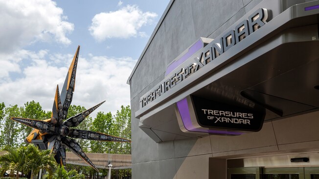 A spaceship sits outside of a large building with a sign saying ‘Treasures of Xandar’
