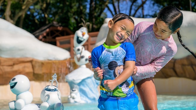 2 young Guests next to sculptures of little snowmen at Tikes Peak water playground in Disney’s Blizzard Beach water park