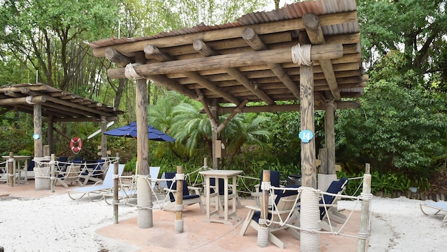 A covered lounge outdoors featuring chairs and tables at Disney’s Typhoon Lagoon water park