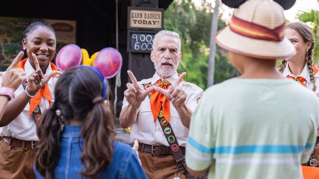 Three Cast Members explaining to Guests how to do bird inspired hand signs at Disney's Animal Kingdom theme park