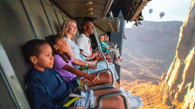A family of 4 Guests flying through a canyon with hot air balloons during Soarin’ Around the World