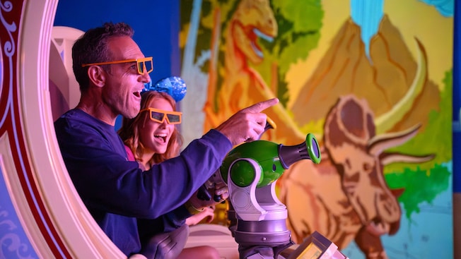 Visitantes apuntando y disparando a una pantalla en la atracción Toy Story Midway Mania en Disney California Adventure Park