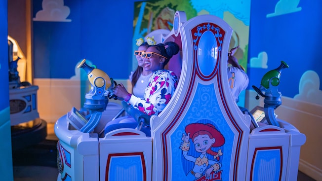 Dos Visitantes apuntan con sus lanzadores a una pantalla en la atracción Toy Story Midway Mania en Disney California Adventure Park