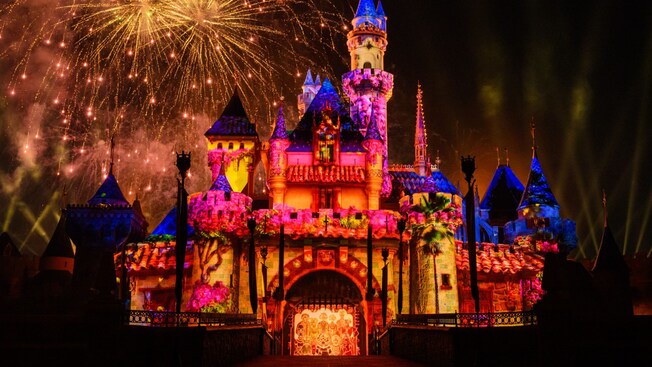 Sleeping Beauty Castle illuminated at night with lighting and fireworks