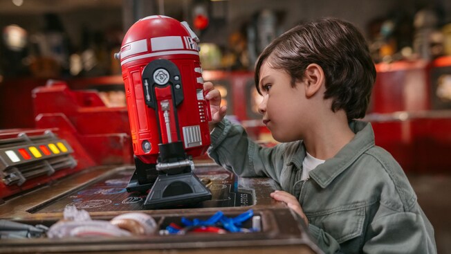 A young boy examining an assembled droid resting on a workbench at Droid Depot  