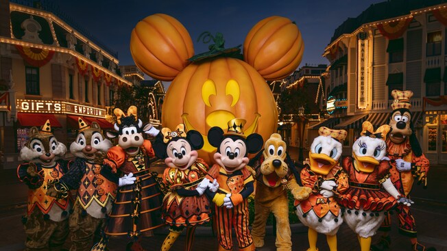 Mickey Mouse, Minnie Mouse and friends wearing Halloween themed outfits while standing on Main Street USA at Disneyland Park