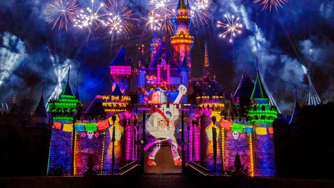 Miguel from 'Coco' holding a guitar projected against the lit-up Sleeping Beauty Castle at Disneyland Park during the show, Together Forever, A Pixar Nighttime Spectacular  