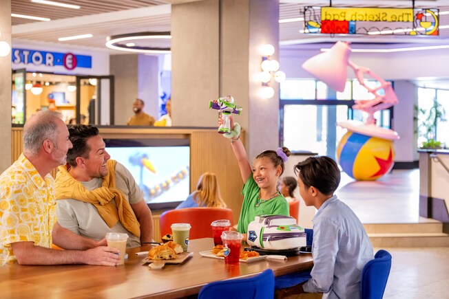 A girl showing off her Buzz Lightyear toy to her family at the Great Maple Modern American Eatery inside the Pixar Place Hotel.