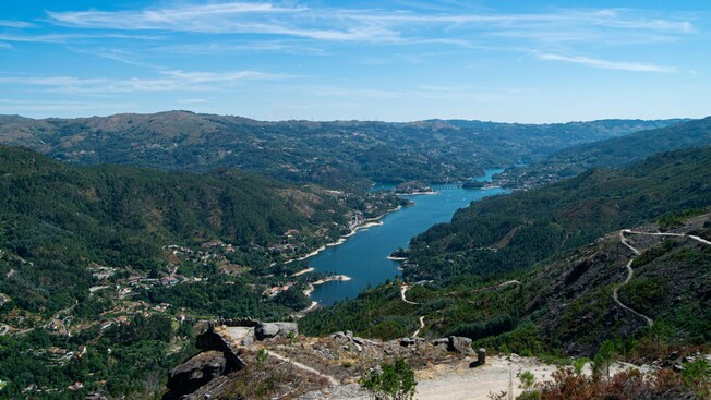 A lush mountainous valley overlooking the water with houses dotting the countryside