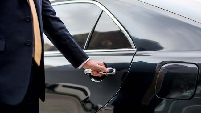 A driver opens the door to a sedan A driver opens the door to a sedan