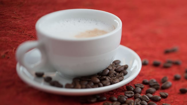 Coffee beans scattered near a cup of coffee