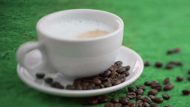 A cappuccino on a plate sprinkled with coffee beans