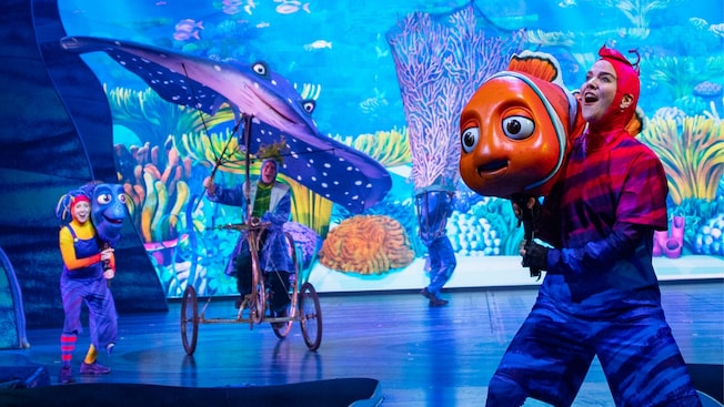 Performers with puppets depicting Marlin, Dory, Nemo and Mister Ray on a stage
