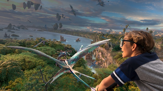 A boy flies through the sky with Na'vi and Mountain Banshees through the skies over Pandora