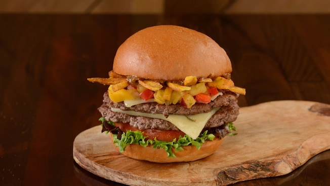 A burger with 2 patties served on a wood slab