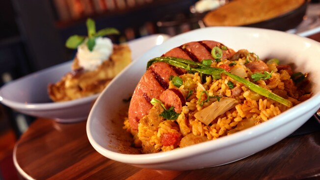 Platillo principal servido con arroz y verduras y un postre cubierto con crema