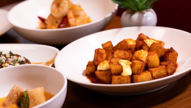 Cuatro platos con sopa, camarones y papas