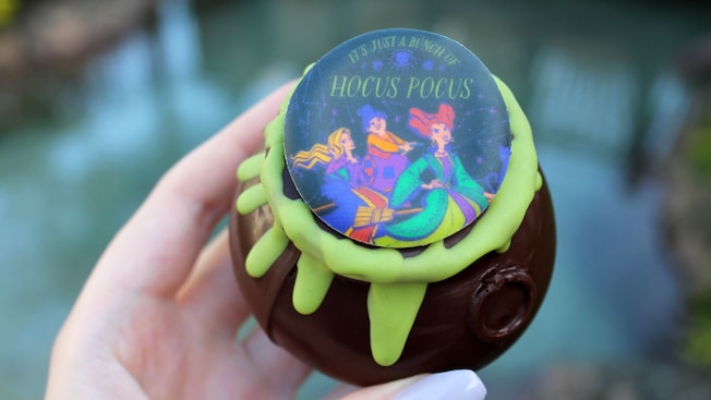 A chocolate cauldron topped with a candy piece depicting the Sanderson Sisters from Hocus Pocus