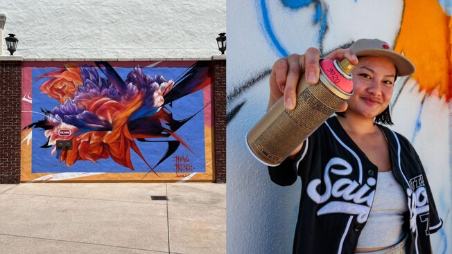 An abstract mural of a flower painted on a wall in Disney Springs at Walt Disney World Resort. Artist Thao French stands in front of a mural smiling and holding a can of spray paint.