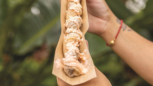 A person holding an Orange Sorbet Churro from Sunshine Churros at Disney Springs Marketplace