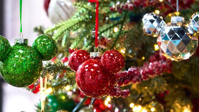 Cuatro adornos con el ícono de Mickey colgados en un árbol