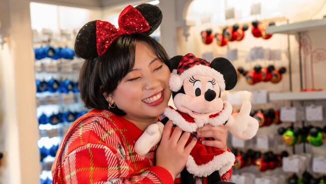 Un Visitante abrazando un peluche de Minnie Mouse vestida de Santa