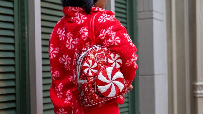 Un Visitante con una chaqueta de polar con el ícono de Mickey de menta y una mochila Loungefly