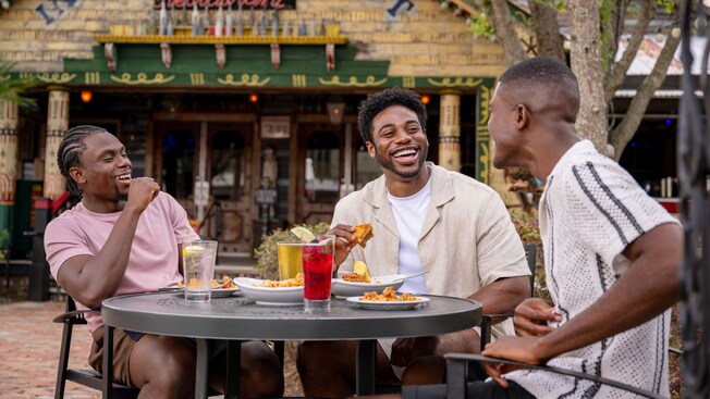 Three men dining outside at a table on the patio near House of Blues Restaurant & Bar