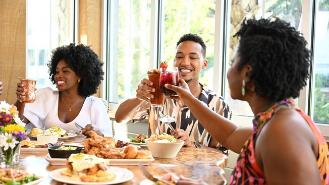 Three Guests dining at a table and making a toast inside Chef Art Smiths Homecomin'