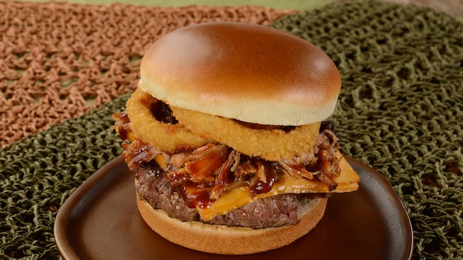 A cheeseburger with barbeque pulled pork and two large onion rings