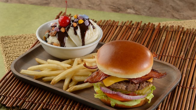 A tray holding a cheeseburger, French fries and an ice cream sundae topped with chocolate sauce