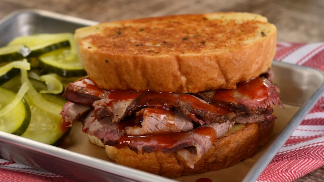 Sliced brisket in between two thick slices of bread and a side of vegetables 