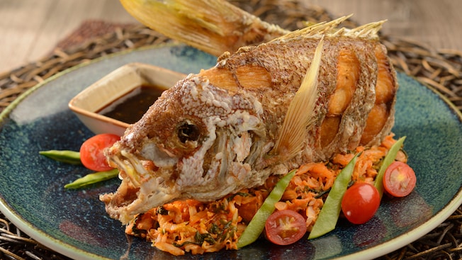 A whole, fried fish paired with scallions and rice