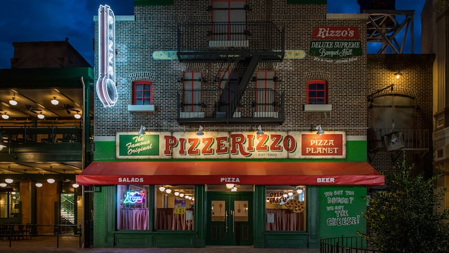 A vibrant sign and fire escape adorn the brick exterior of PizzeRizzo at Disneyâs Hollywood Studios
