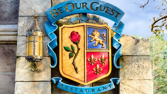 The coat-of-arms signage outside Be Our Guest restaurant