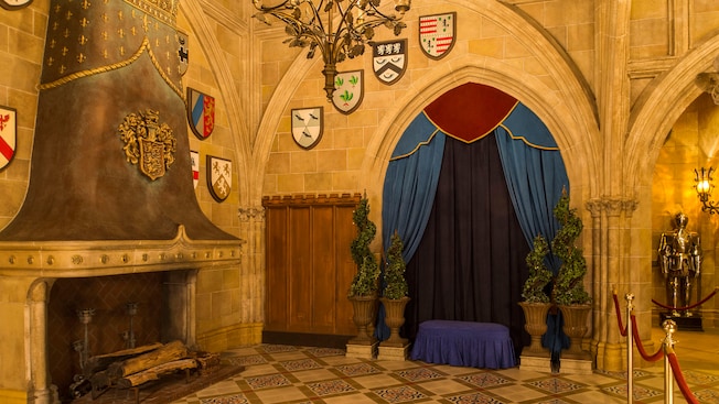 Stone fireplace and curtained gothic archway  with medieval heraldry lining stone walls
