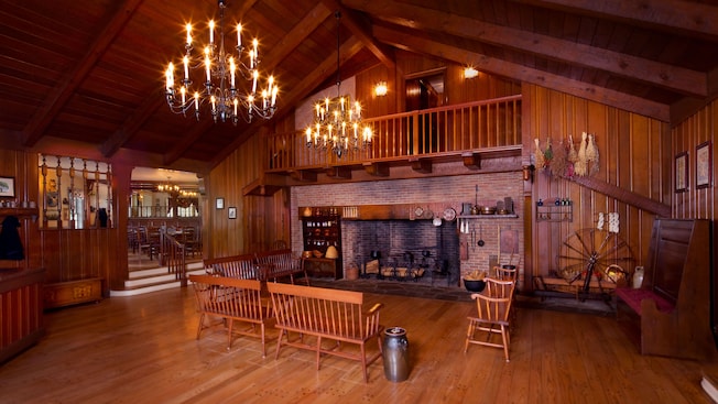 Early American-inspired waiting hall with stone fireplace, benches and chandeliers