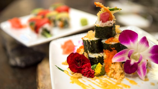 An appetizing plate of maki sushi is artfully decorated with salmon roe and exotic flowers