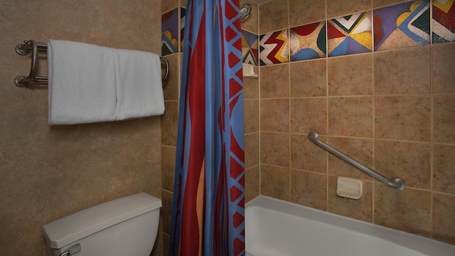 Um vaso sanitário e um toalheiro ao lado de um chuveiro com banheira e corrimão 