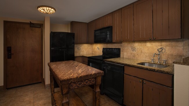 Cozinha com balcão de granito, lava-louças, fogão, forno micro-ondas, geladeira completa e ilha de cozinha