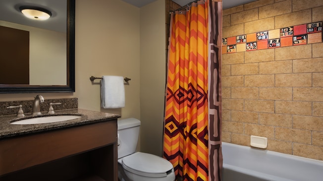 Um banheiro com chuveiro e banheira, cortina no box com tema africano e quadro 