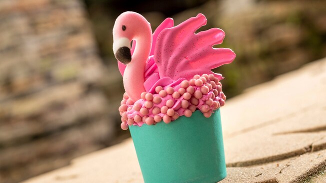 A cupcake topped with frosting and a candy flamingo