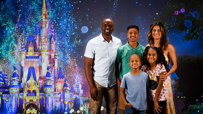 Parents and their 3 kids pose for a picture and an image of Cinderella Castle
