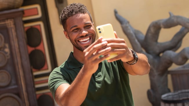 A person smiles and takes a selfie using a mobile phone
